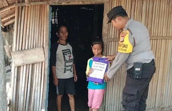 Bhabinkamtibmas saat menyerahkan bantuan kepada anak kurang mampu (Dok : ist).