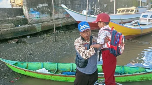 Anggota Satpolair, Bripka Muhammadong  memantau situasi dan memberikan bantuan langsung kepada siswa dalam menaiki perahu sampan (Dok : Ist)
